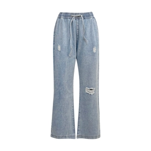 Dettaglio di jeans azzurri con coulisse elastica in vita e texture denim usurata con strappi