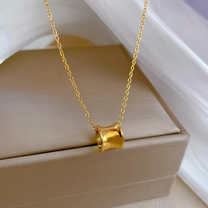 Close-up of golden waist-shaped pendant on silk fabric inside a gift box
