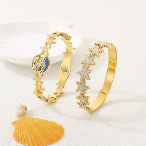 Detailaufnahme goldener Armbänder mit Stern-, Mond- und Palmenanhängern im Meeres-Stil