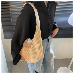 Detail showing beige woven straw shoulder bag with mesh texture for summer beach vacation