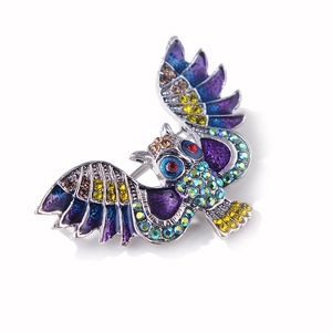 Détail d'une broche hibou vintage avec strass colorés et ailes en émail poli