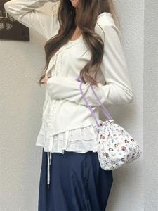 Quilted cartoon bucket bag with purple drawstring straps shown in use on white outfit