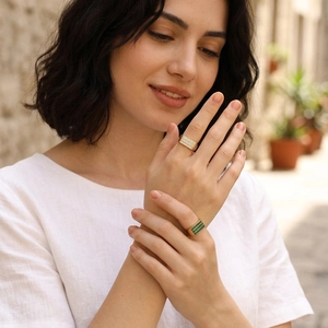 Detailed view of 18K gold plated signet rings with emerald and zircon stone settings