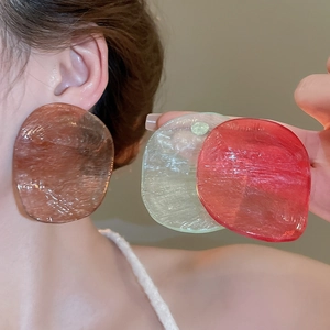 Detailed view of oversized irregular resin earrings in brown, green, and red colors