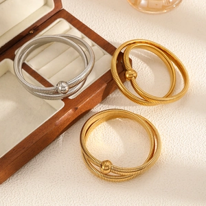 Detail of multi-strand gold and silver snake chain bracelets with metallic ball ends