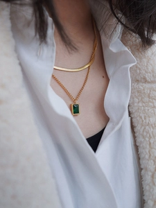 Detail of vintage emerald green zircon necklace featuring a layered golden snake bone chain