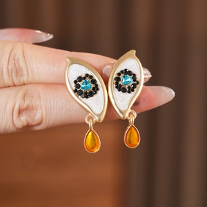 Detailed macro shot of vintage eye earrings with blue heart and yellow droplet