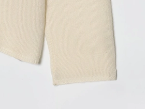 Close-up of cream wool blend knitwear showing delicate texture and smooth hem finish