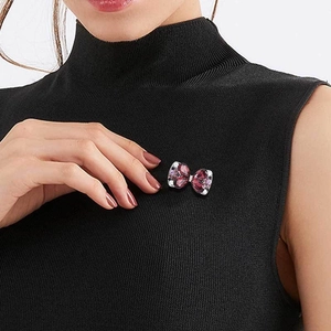 Elegant silver butterfly brooch with purple and pink crystals pinned on black collar