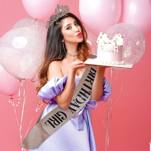 Model wearing a rose gold glitter Birthday Girl sash with black lettering at a party