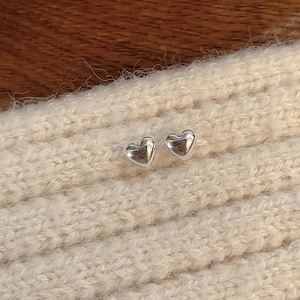 S925 sterling silver heart stud earrings pair on a soft textured knit background