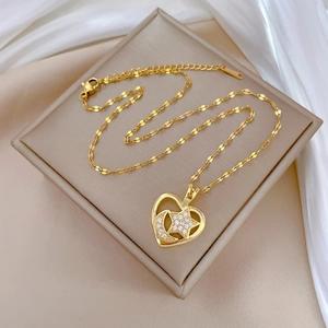 Detailed macro of gold heart pendant with crescent moon and stars on silk padding