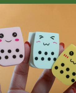 Close-up of three milk tea cup shaped makeup sponges in pink, blue, and yellow colors