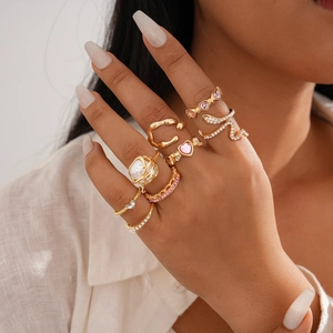 Detail shot of gold-tone eight-piece ring set with crystals and pearls on model hands