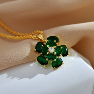 Macro detail of gold flower pendant necklace with malachite petals on silk fabric