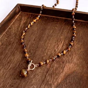 Tiger eye stone necklace with gold toggle clasp and large sphere pendant on wood