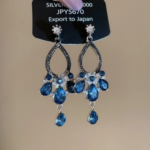 Detailed close-up of blue teardrop crystal earrings with 925 silver needles and tassels