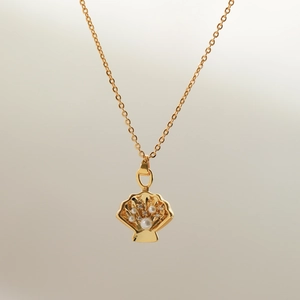 Macro detail of gold seashell pendant with white pearls and sparkling zircons