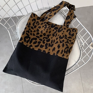Detail of leopard print tote bag texture and black canvas stitching on a mesh chair