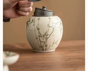 Macro detail of hand placing a metal lid on a ceramic tea canister with bamboo patterns