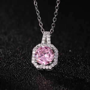 Detailed close-up of pink gemstone pendant with halo of zircons on black background