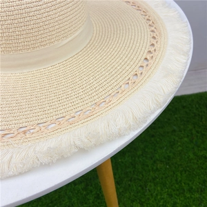 Dettaglio cappello di paglia con trama traforata e bordi con frange bianche eleganti