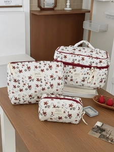 Detailed set of three quilted corduroy makeup bags with red floral patterns on wood