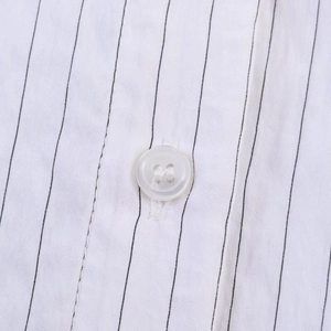 Close-up of white fabric with black stripes showing fine texture and a four-hole button