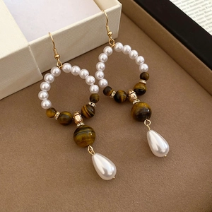 Detail of vintage tiger eye and pearl long drop earrings with gold finish and rhinestones