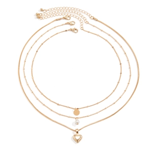 Detailed view of triple-layered gold necklace with faux pearls and heart pendant charms