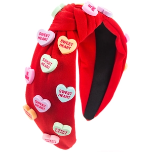 Détail du bandeau rouge noué avec des breloques colorées en forme de cœur lettré