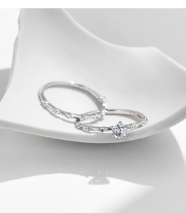 Close-up of sparkling moissanite solitaire and wedding band set on white ceramic