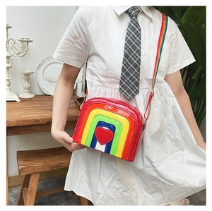 Detail view of rainbow striped crossbody bag with central red heart and adjustable strap