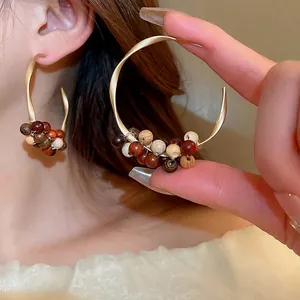 Retro C-shaped hoop earrings with sandalwood beads and matte gold finish worn by model