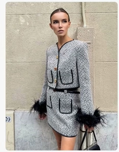 Detail of tweed suit with black feather cuffs, gold buttons, and leather trim styling