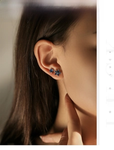 Close-up of elegant asymmetrical blue square gem and flower silver stud earrings on model