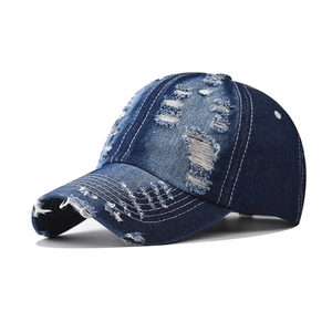 Close-up of distressed denim baseball cap with white contrast stitching and frayed edges