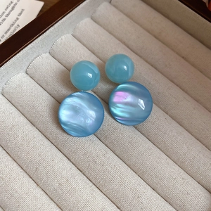 Detailed close-up of blue resin drop earrings with iridescent luster on fabric