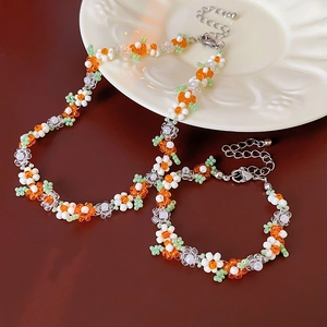 Detailed shot of handmade orange and white daisy flower bead necklace and bracelet set
