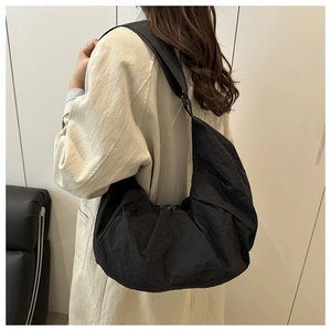 Detail of black nylon crescent bag showing pleated texture and adjustable strap on model