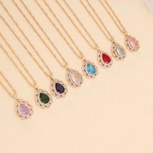 Collection of teardrop crystal necklaces in eight vibrant colors on gold chains