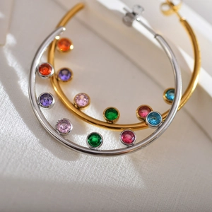 Close-up of gold and silver hoop earrings with vibrant colorful cubic zirconia stones