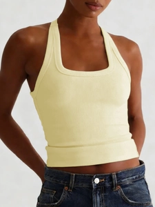 Detailansicht eines gelben gerippten Halterneck-Yoga-Tops kombiniert mit blauen Jeans