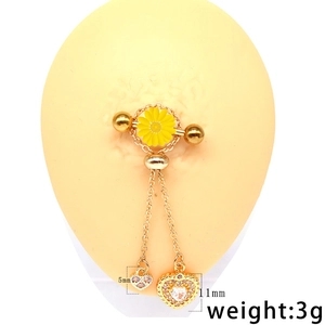 Macro view of gold chain nipple ring with yellow daisy and heart pendants on model