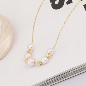 Minimalist S925 silver necklace with white freshwater pearls and gold beads on a shell prop