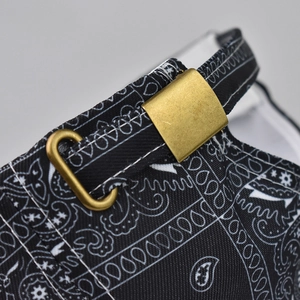 Macro detail of adjustable metal buckle and paisley print on black baseball cap