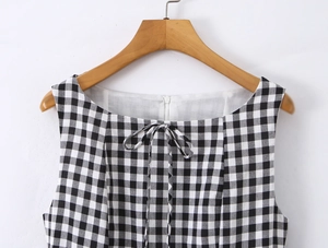 Detail of black and white gingham dress showing the tied bow neckline and fabric texture