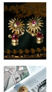 Detailed shot of vintage gold sunflower earrings with pink teardrop crystal on a magazine