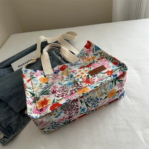 Floral canvas tote bag with large capacity, featuring a long shoulder strap and side pockets