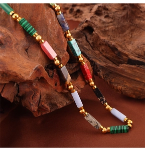 Macro detail of natural colorful rectangular beads with gold accents on rustic wood